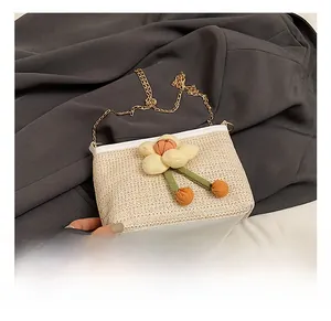 Détail du sac seau en paille tressée avec fleurs 3D et bandoulière en chaîne dorée