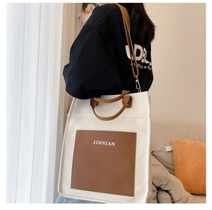 Detailed shot of beige canvas tote with brown leather trim and JINNIAN logo print