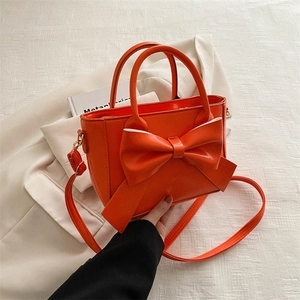 Fashionable orange tote bag with large bow decoration and adjustable shoulder strap