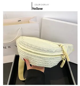 Close-up of yellow quilted chest bag with dual zippers and adjustable fabric strap