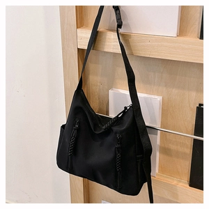Détail du sac fourre-tout noir en nylon avec zips verticaux et tirettes tressées sur un support