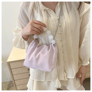 Détail du sac seau plissé violet avec une grande poignée en perles blanches élégantes