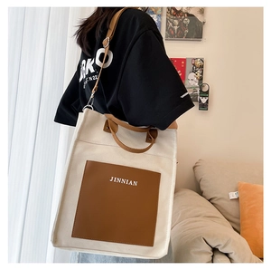 Detail of white canvas tote with brown leather pocket and adjustable shoulder strap