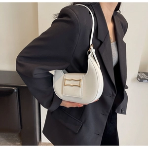 Detail of white crescent shoulder bag featuring a vintage gold metal buckle and smooth leather