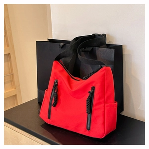 Vue détaillée du sac fourre-tout en nylon rouge avec zips noirs et poche latérale