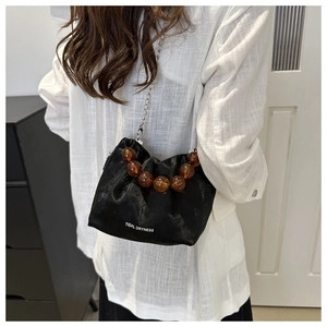Détail du sac seau en satin noir avec perles d'ambre et bandoulière chaîne argentée