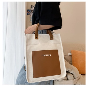 Detailed shot of large canvas tote bag with brown contrast pocket and top handles