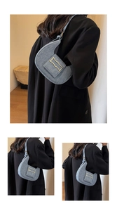 Detail of denim blue crescent shoulder bag with golden wave buckle and sleek denim strap