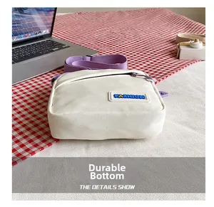 Détail du fond résistant à l'usure de ce petit sac bandoulière en toile blanche tendance