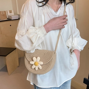 Beige hand-woven straw crossbody bag with white daisy flower detail for summer beach vacations