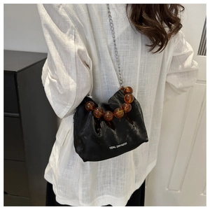 Détail du sac seau plissé noir avec perles ambrées et texte imprimé Tidal Dryness