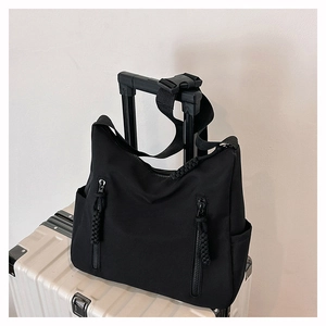 Détail d'un sac cabas en nylon imperméable avec deux poches zippées sur une valise blanche
