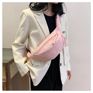 Pink embossed chest bag with textured surface shown on model with adjustable strap