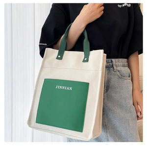 Detail of canvas tote bag with green pocket showing JINNIAN logo and large capacity