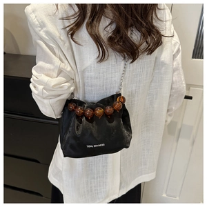 Détail du sac nuage plissé noir avec perles ambrées et bandoulière chaîne argentée