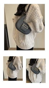 Close-up of black crescent shoulder bag with golden metal buckle and leather texture
