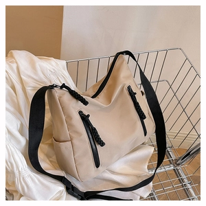 Vue détaillée du sac fourre-tout en nylon beige avec fermetures éclair noires dans un chariot