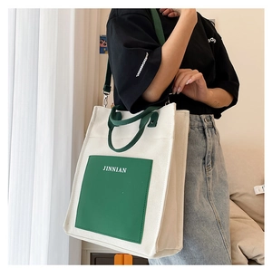 Detail of color-block canvas tote bag with adjustable shoulder strap and JINNIAN logo