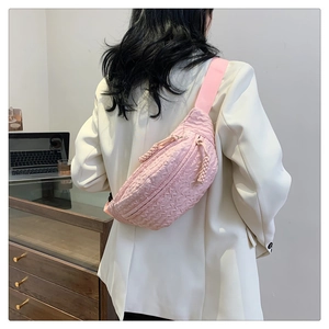 Pink crossbody bag with quilted texture shown on model in modern interior setting