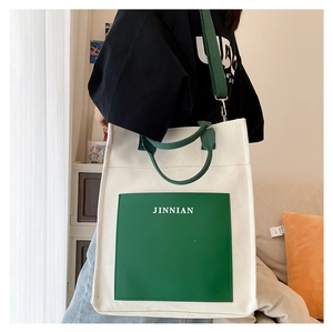 Detail view of large canvas tote bag with green front pocket and wide shoulder strap