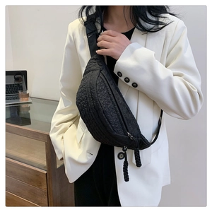 Quilted texture detail on black crescent chest bag with woven rope zipper pulls