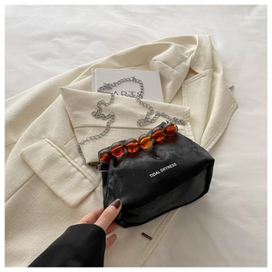 Détail du sac seau en satin noir avec perles en ambre et bandoulière chaîne
