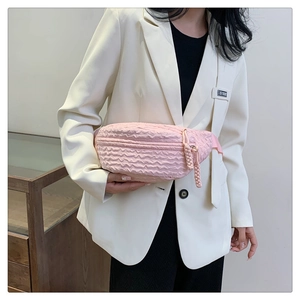 Detailed close-up of pink textured bubble fabric waist bag with woven zipper pull strap