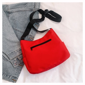 Détail du grand sac fourre-tout rouge en nylon avec poche zippée noire et sangle réglable