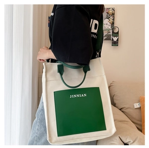 Detail of minimalist large canvas tote bag with contrast green straps and JINNIAN logo