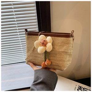 Détail d'un sac seau en paille tressée avec bordure en cuir et breloque fleur