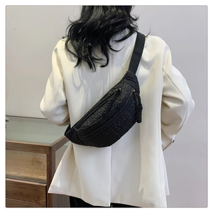 Detail of black wave textured fanny pack featuring a braided zipper pull and adjustable strap