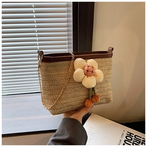 Détail du sac seau en paille tissé à la main avec bordure en cuir et breloque florale
