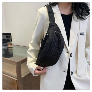 Detail of black pleated texture crossbody chest bag with adjustable nylon shoulder strap