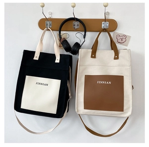 Detail of color-block canvas handbags in black and beige with adjustable shoulder straps