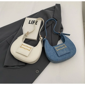 Close-up of minimalist half-moon bags in cream leather and blue denim with gold buckles