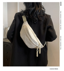 Close-up of white quilted crossbody chest bag with unique wrinkled texture and dual woven zipper pulls