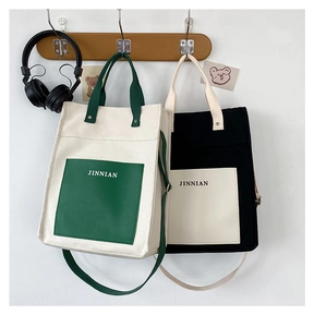 Detail of minimalist canvas tote bags with contrast pockets and JINNIAN lettering