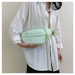 Detail of mint green chest bag featuring unique bubble textured fabric and woven zip puller