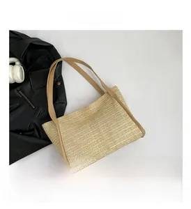 Detailed view of woven straw tote bag texture with brown leather handles on white background