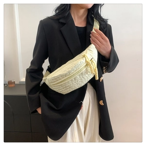 Detail of light yellow textured bubble fabric crossbody bag with woven zipper pull