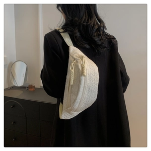 Detail of white quilted texture belt bag showing dual zippers and woven puller detail