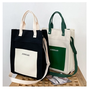 Close-up of contrast color canvas tote bags with JINNIAN logo on a wooden bench