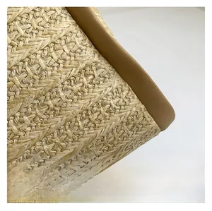 Close-up detail of woven straw texture with premium dark brown leather trim on tote bag