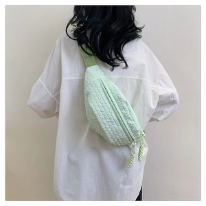 Detail of mint green crossbody bag featuring textured bubble fabric and woven zipper pull