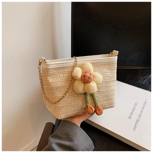 Détail du sac bandoulière en paille beige avec garniture en cuir blanc et pendentif fleur