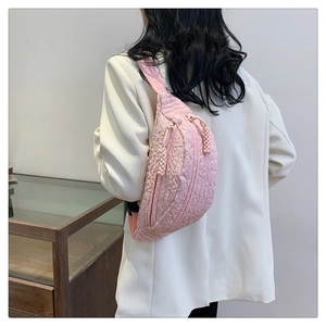 Detail of pink quilted waist bag showing pleated texture and woven zipper pull on strap