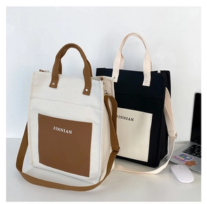 Detail view of large color-block canvas tote bags with shoulder straps and front pockets