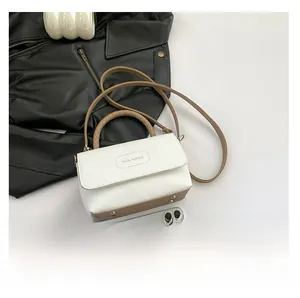 Détail du mini sac bicolore montrant la texture litchi blanc et la base de couleur kaki