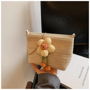Détail du sac seau en paille tressée avec breloque fleur et chaîne dorée pour l'été