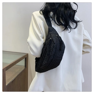 Detail of black quilted crossbody bag with wave texture and durable double zipper closure